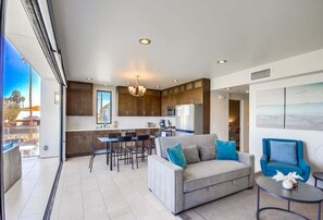 A modern living room with a sofa, a coffee table, and a dining area with chairs. - 3 bed 3 bath in Ocean Beach (San Diego)