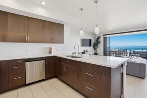 A modern kitchen with a dishwasher, white countertop, and wooden cabinets.