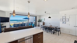 Une cuisine moderne dotée d’un grand îlot central, d’un coin repas et offrant une vue sur la plage.
