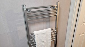 A metal towel rack with multiple shelves, a white towel hanging on one of the shelves, and a door to the right. - Chester Le Street's Emerald 3 Bed House (Chester-le-Street)