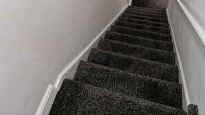 A staircase with carpeted steps leading to a door. - Chester Le Street's Emerald 3 Bed House (Chester-le-Street)