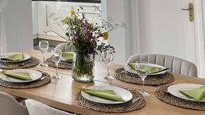 A dining table set with plates, cutlery, and wine glasses, surrounded by chairs. - Villa Fortuna in Nikiana (Lefkada)