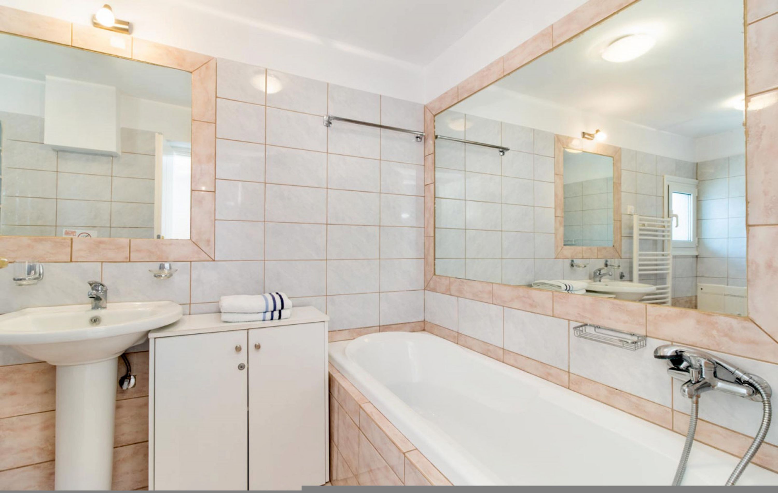 Une salle de bain moderne avec un lavabo, un miroir et une baignoire.