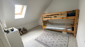 Eine kleine, einzimmerwohnung mit Etagenbett, einem kleinen Schreibtisch mit Lampe, einem Fenster und einem Teppich mit Sternenmuster.