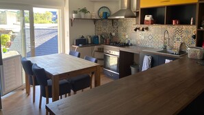 Eine moderne Küche mit einem Holzespeisetisch und -stühlen, einem eingebauten Ofen und einer gelben Akzentwand.