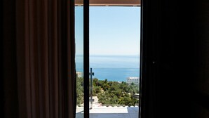 Habitación con cama y vista al mar a través de un ventanal corredizo.
