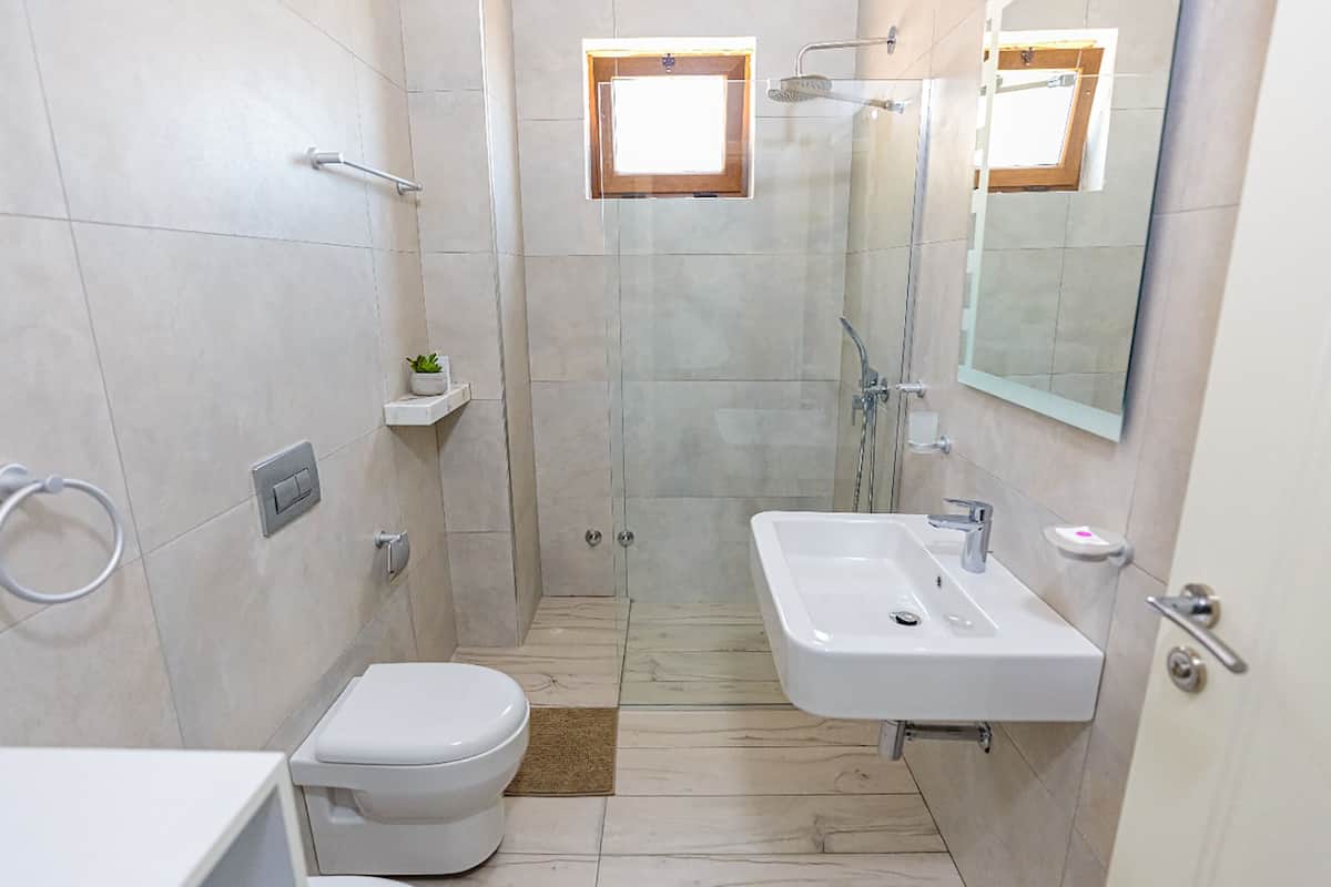 A modern bathroom with a toilet, sink, and shower.