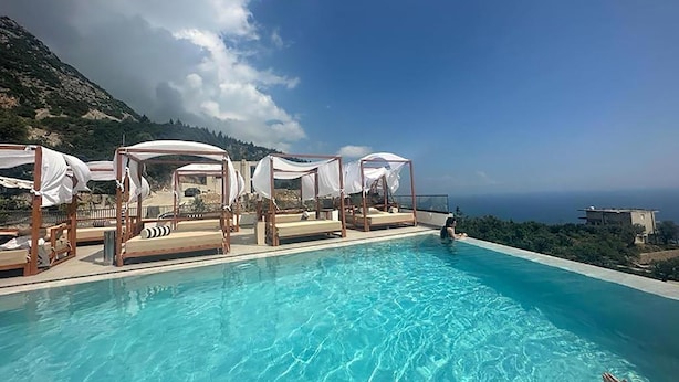 Zona junto a la piscina con tumbonas y vistas al mar.