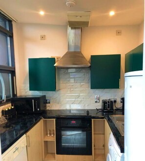 A compact kitchen with a microwave, oven, and a built-in range hood. - Bull's Ring 3bed Penthouse City Centre (Birmingham)