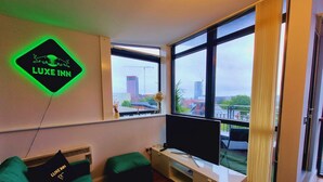 A modern hotel room with a large window, a flat-screen TV, and a neon sign on the wall. - Bull's Ring 3bed Penthouse City Centre (Birmingham)