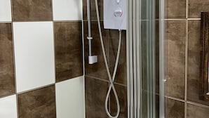 Een douchecabine met een handdouche en een bedieningspaneel aan de muur.