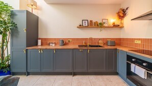 Eine moderne Küche mit grauen Schränken, einer Holz Arbeitsplatte, einer Spüle und einem eingebauten Backofen.