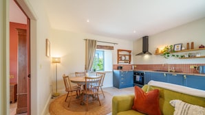 A cozy kitchen with a dining area, a sofa, and a window with curtains.