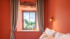 A bedroom with a bed, curtains, a window, and a wall-mounted light fixture.
