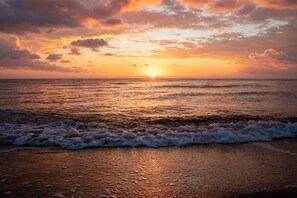 A sunset over the ocean with waves crashing onto the shore. - Captivating Lake & Oceanview Getaway House (Meneou)