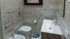 Une salle de bain équipée d’un bidet, de toilettes et d’un lavabo.