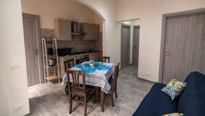Une cuisine moderne avec un coin repas, comprenant une table dressée pour quatre personnes, des meubles de rangement en bois et un four encastré.