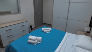 Une chambre d’hôtel avec un lit, une commode, un miroir et une porte.