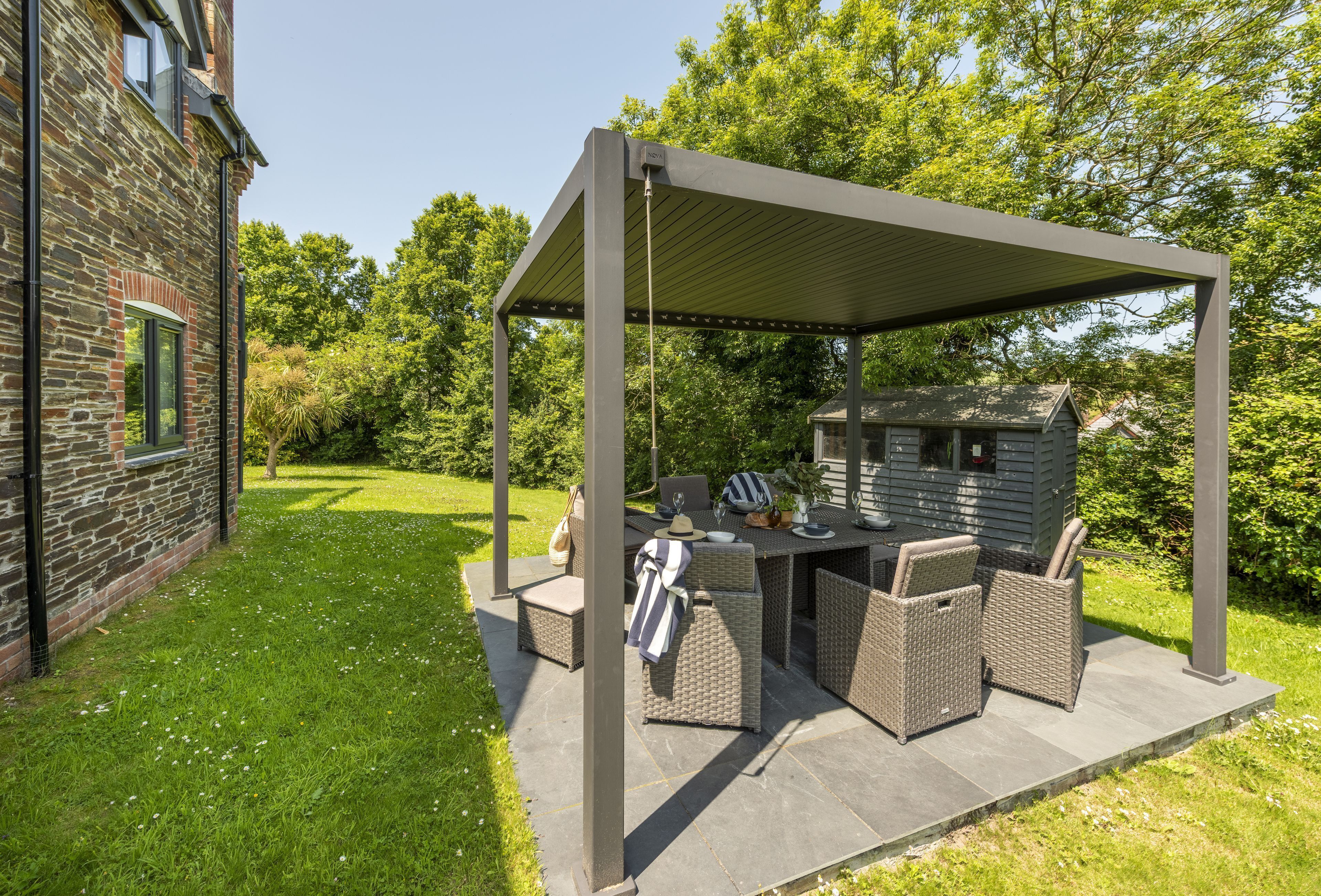 A covered patio area with outdoor furniture, a table, and a small shed.