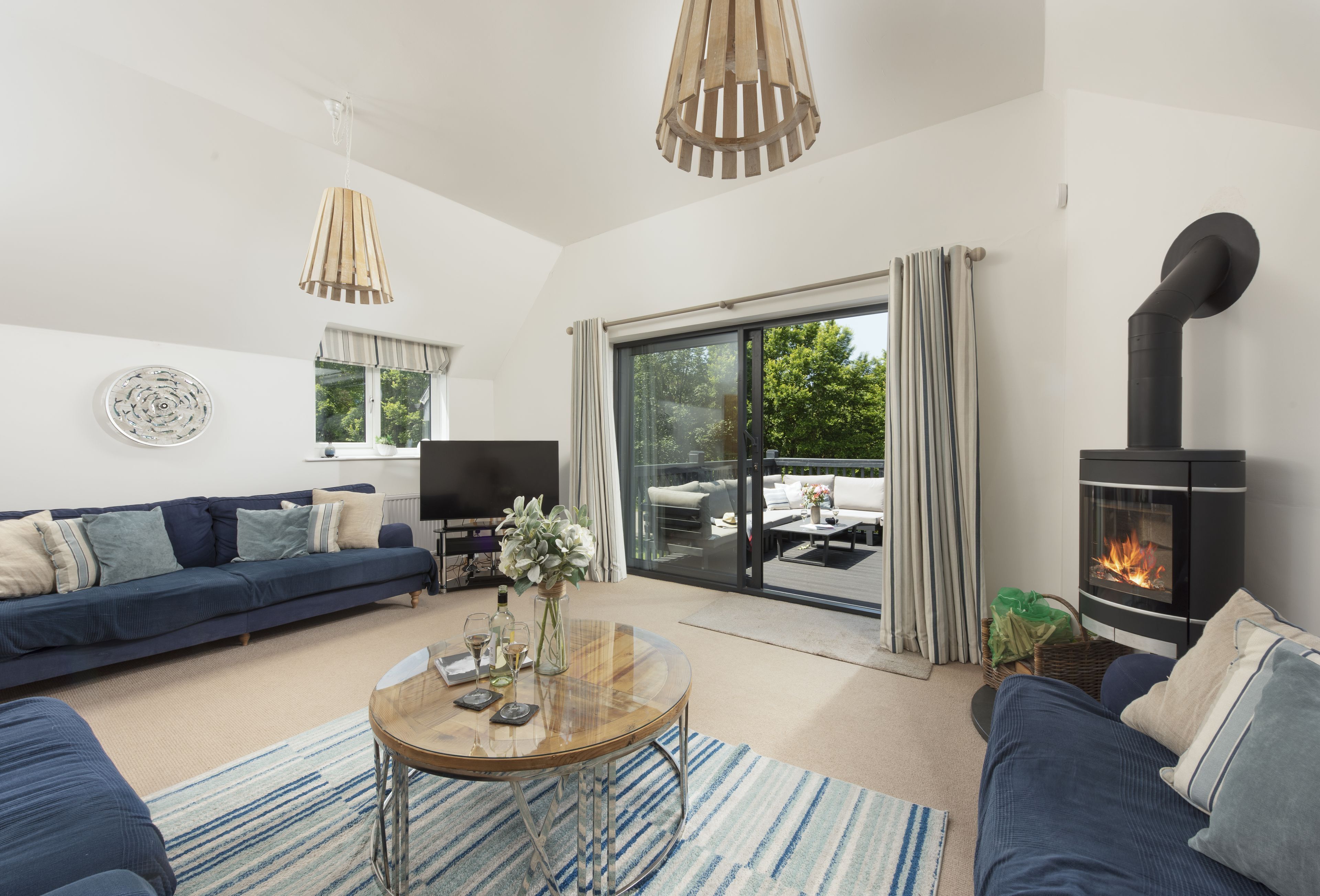 A modern living room with a sofa, a coffee table, a fireplace, and a sliding glass door leading to an outdoor area.