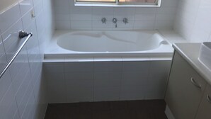 A bathroom with a bathtub, a window, and a towel rack.