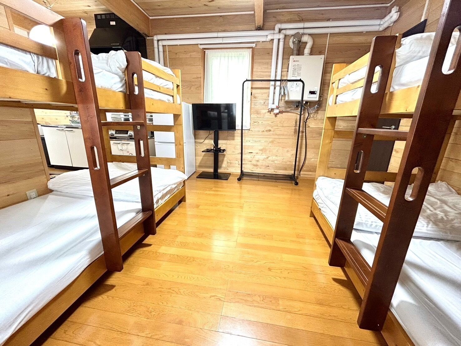 A bunk bed room with wooden floors and a heater.