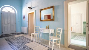 A room with a patterned rug, white chairs, a small table, and a mirror on the wall. - Antica Dimora del Platano - F4856 (Nurachi)