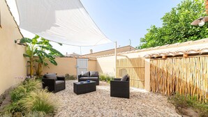 An outdoor patio area with stone flooring, two black wicker sofas, a small table, and a white canopy. - Antica Dimora del Platano - F4856 (Nurachi)