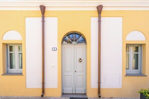 Fachada de edificio con puerta doble, dos ventanas y un pequeño balcón.