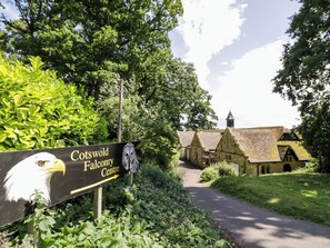 A sign for Cotswold Falconry Centre with a pathway leading to traditional stone buildings. - Ross Cottage (Evesham)
