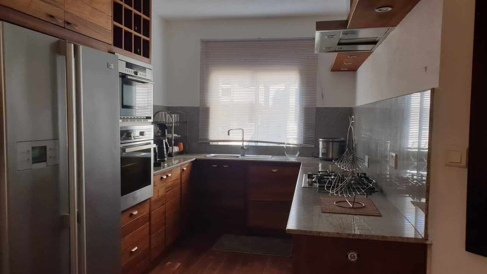 Een moderne keuken met roestvrijstalen apparatuur, houten keukenkastjes en een groot raam voor natuurlijk licht.