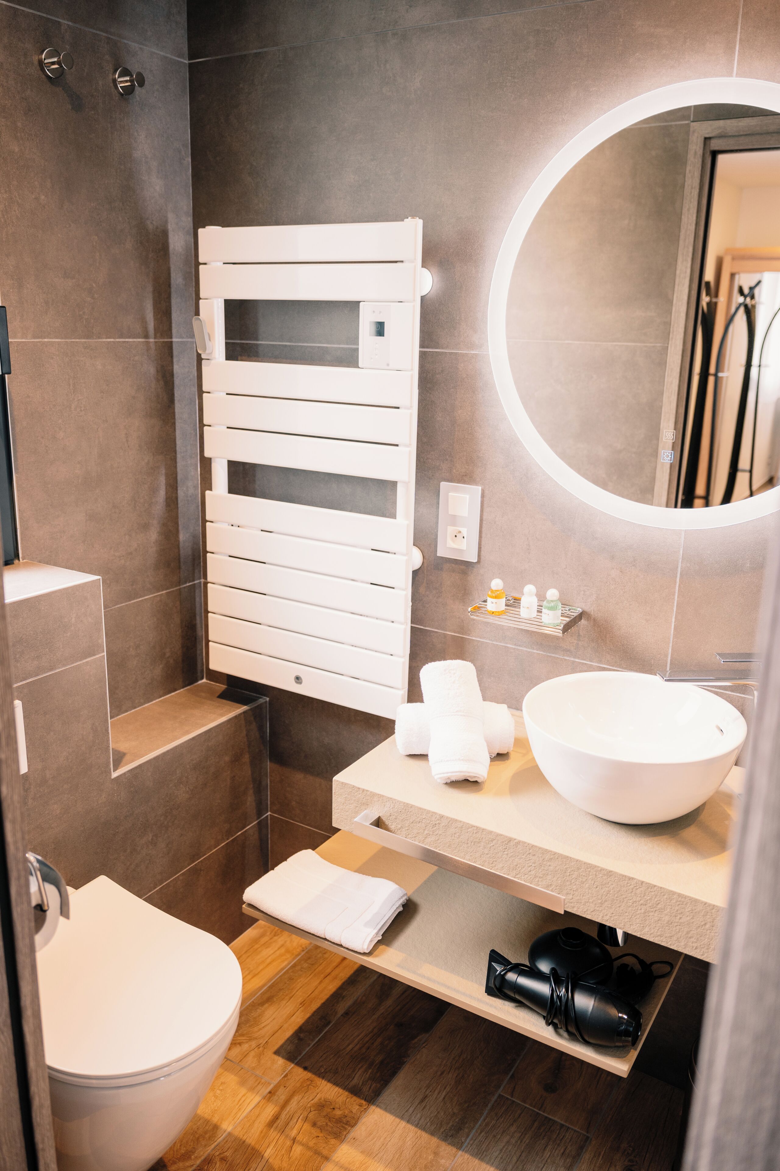 A modern bathroom with a white toilet, a large sink, a mirror, and a towel rack.