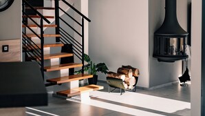 Un intérieur moderne avec un escalier, une cheminée et une horloge au mur.