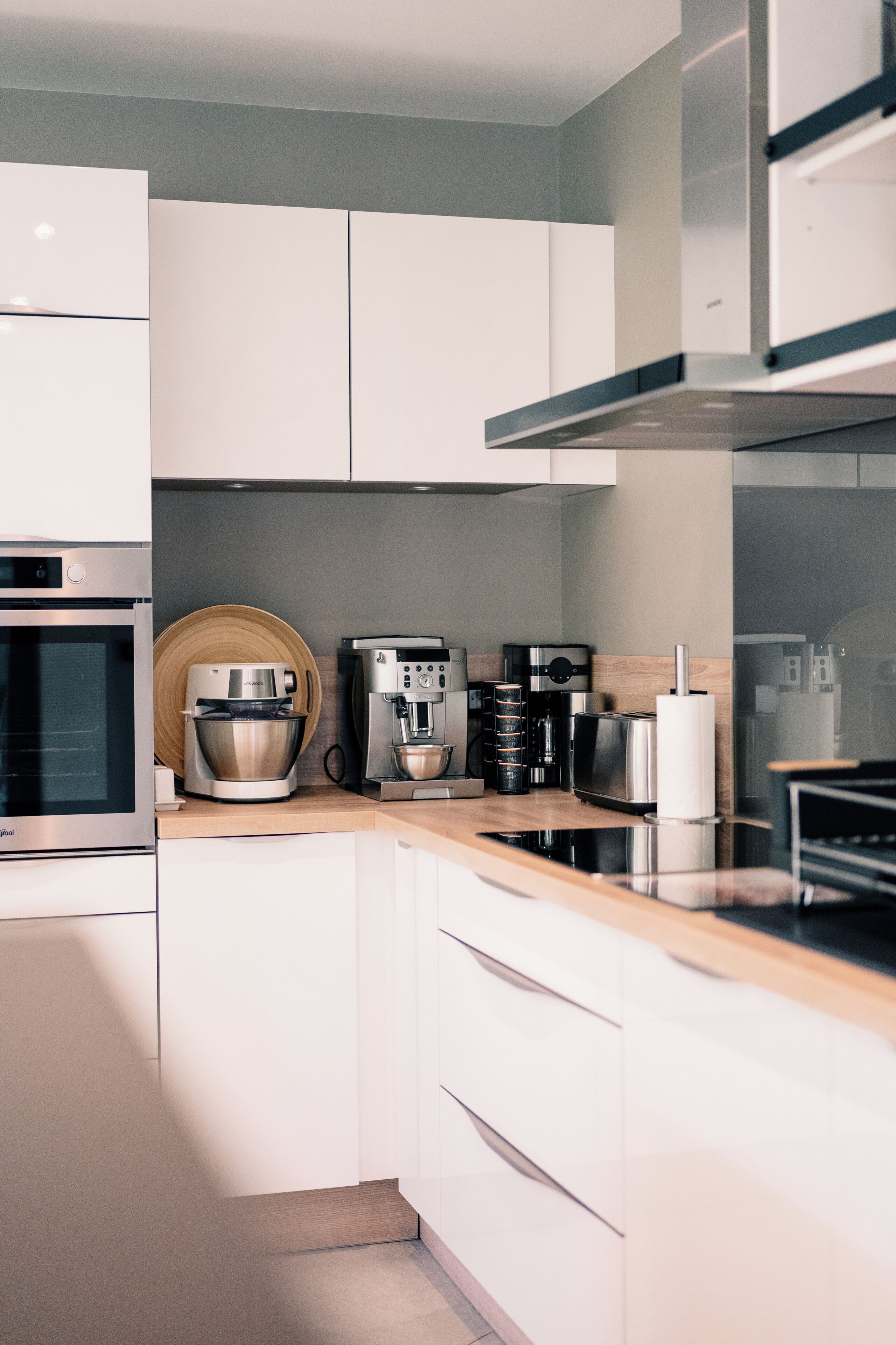 Una cucina moderna con elettrodomestici in acciaio inossidabile, piani in legno e mobili bianchi.