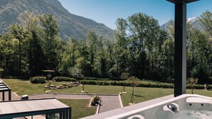 Un bain à remous avec vue sur les montagnes, un espace salon extérieur et une terrasse couverte.