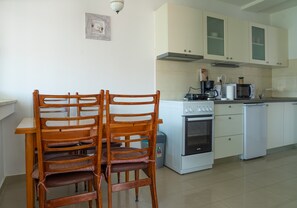 A kitchen with white cabinets, a microwave, a stove, and a sink. There are two wooden chairs at a table. - Spacious apt few min Walk to old Town and Beach (Split)