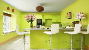 A modern kitchen with green cabinets, white bar stools, and a central island. - Fell End - Sleeping 8+5 guests in 4 bedrooms (Brampton)