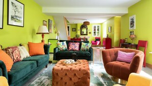 A living room with a green wall, a green sofa, a brown ottoman, and a red armchair. - Fell End - Sleeping 8+5 guests in 4 bedrooms (Brampton)