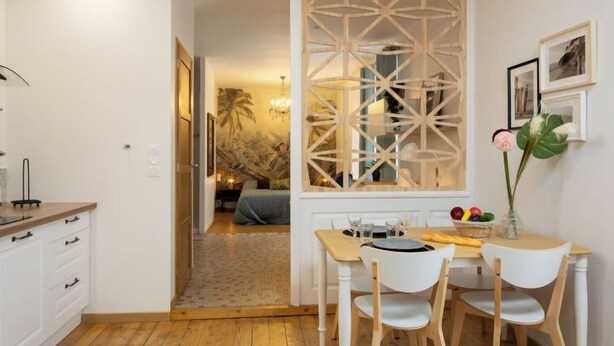 Una cocina moderna con armarios blancos, encimera de madera y comedor con sillas y mesa blancos.