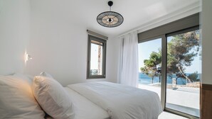 A bedroom with a large bed, a window, and a view of the sea. - Boutique villa with private pool in Alonissos island, Greece. Stunning sea view. (Votsi)
