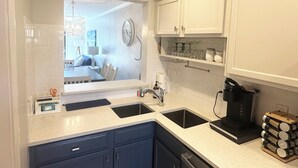 Una cucina moderna con mobili bianchi, una macchina da caffè nera e un lavello.