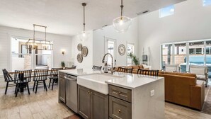 Una cocina moderna con una isla grande, armarios oscuros e iluminación colgante.