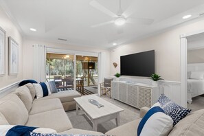 A living room with a sofa, coffee table, TV, and a ceiling fan.