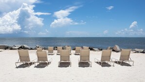 A beach with rows of beige lounge chairs facing the ocean. - Seabrook Exclusives | 1144 Summerwind (Johns Island)