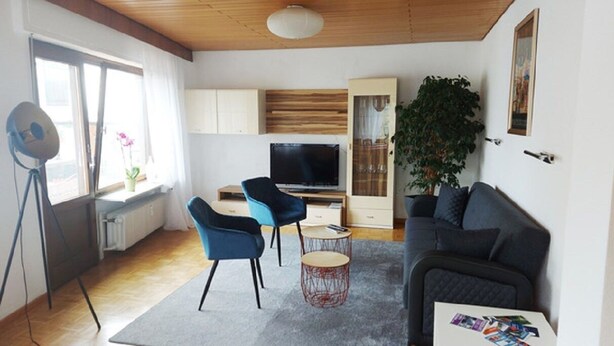 A modern living room with a sofa, two chairs, a TV, and a large plant. - fewo-herrheinspaziert (Oberwesel)