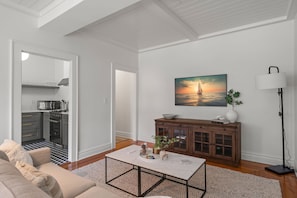 Ein modernes Wohnzimmer mit Sofa, Couchtisch und einem Gemälde, das einen Sonnenuntergang über dem Meer zeigt.