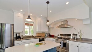 Une cuisine moderne dotée d’appareils électroménagers en acier inoxydable, de meubles blancs et d’un îlot central.