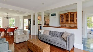 Un salon spacieux avec un canapé gris, une table basse en bois et un coin repas avec des chaises rouges.