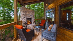 A wooden deck with stone fireplace, wicker chairs, and a sofa with cushions. - Smoky Mtn Haven w/Indoor Pool, Theater, Game Room (Sevierville)