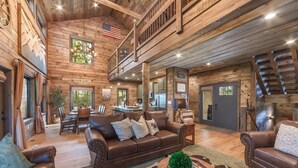 A spacious living area with a high ceiling, wooden walls, a dining area, and a kitchen. - Smoky Mtn Haven w/Indoor Pool, Theater, Game Room (Sevierville)